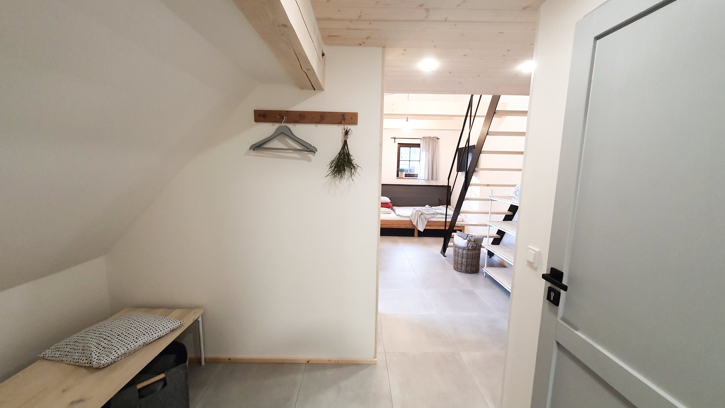 Vstupní chodba apartmánu III: lavice, věšák a pohled do obytného prostoru