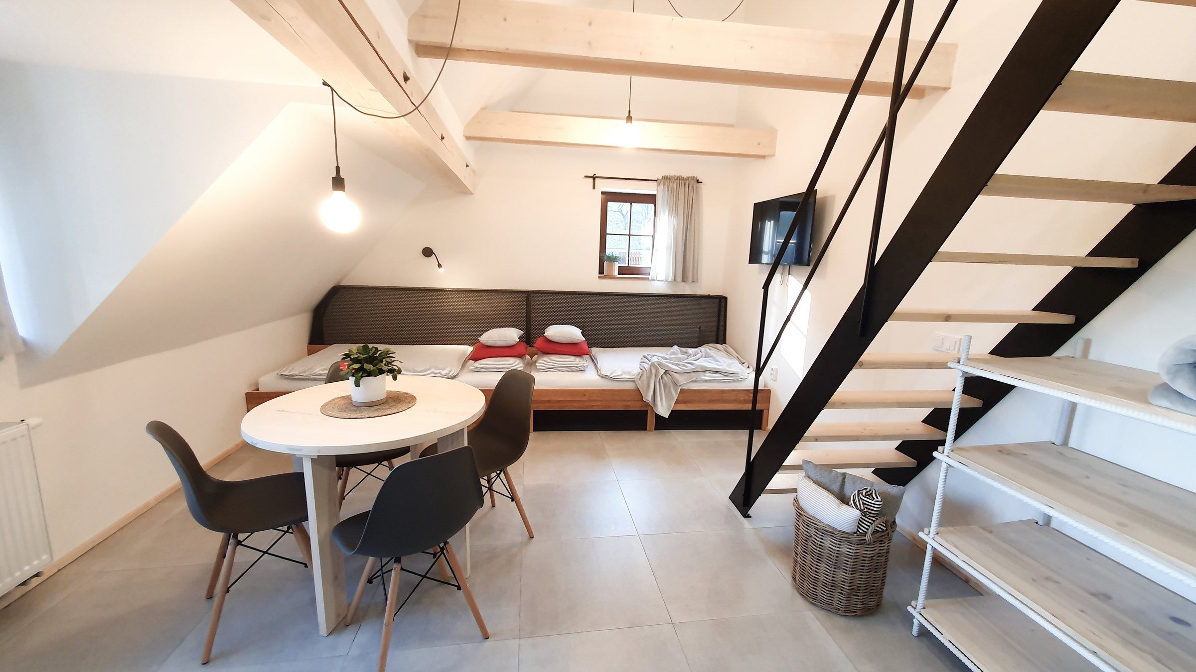 Kulatý stůl a lůžka pod střechou v apartmánu III